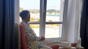 A person seated on a bench by a window with a view of a cityscape. - F2 Sea and Morgat beach view with small balcony (Crozon)