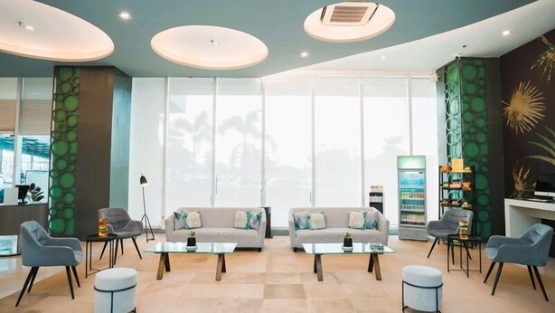 A modern lobby with two sofas, a coffee table, a floor lamp, and a refrigerator. - Go Hotels Iligan (Iligan)