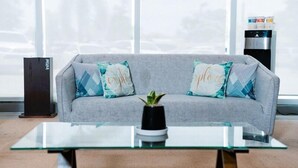 A grey sofa with patterned cushions, a glass coffee table, and a potted plant. - Go Hotels Iligan (Iligan)