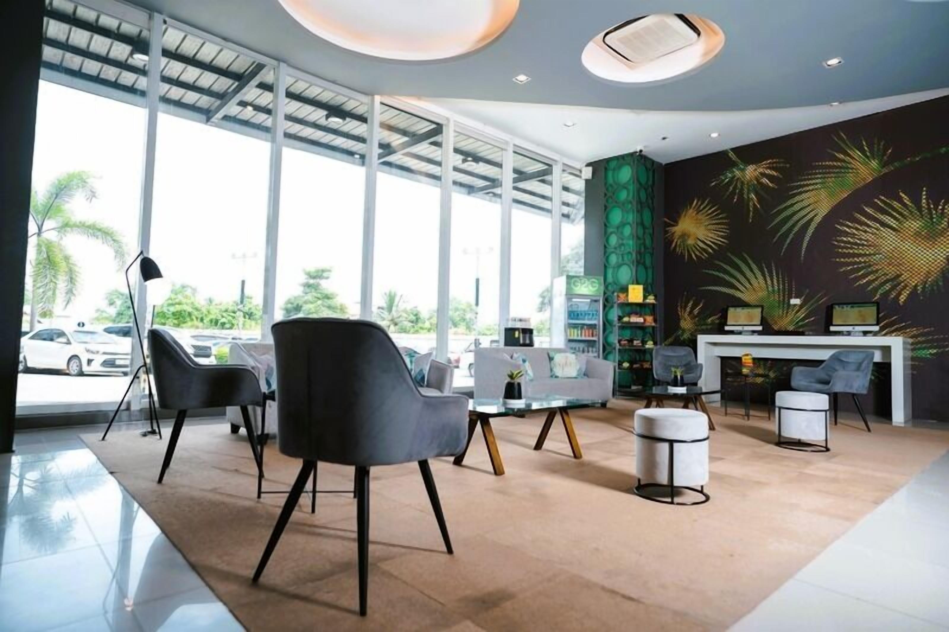 A modern hotel lobby with large windows, a reception desk, and seating areas.