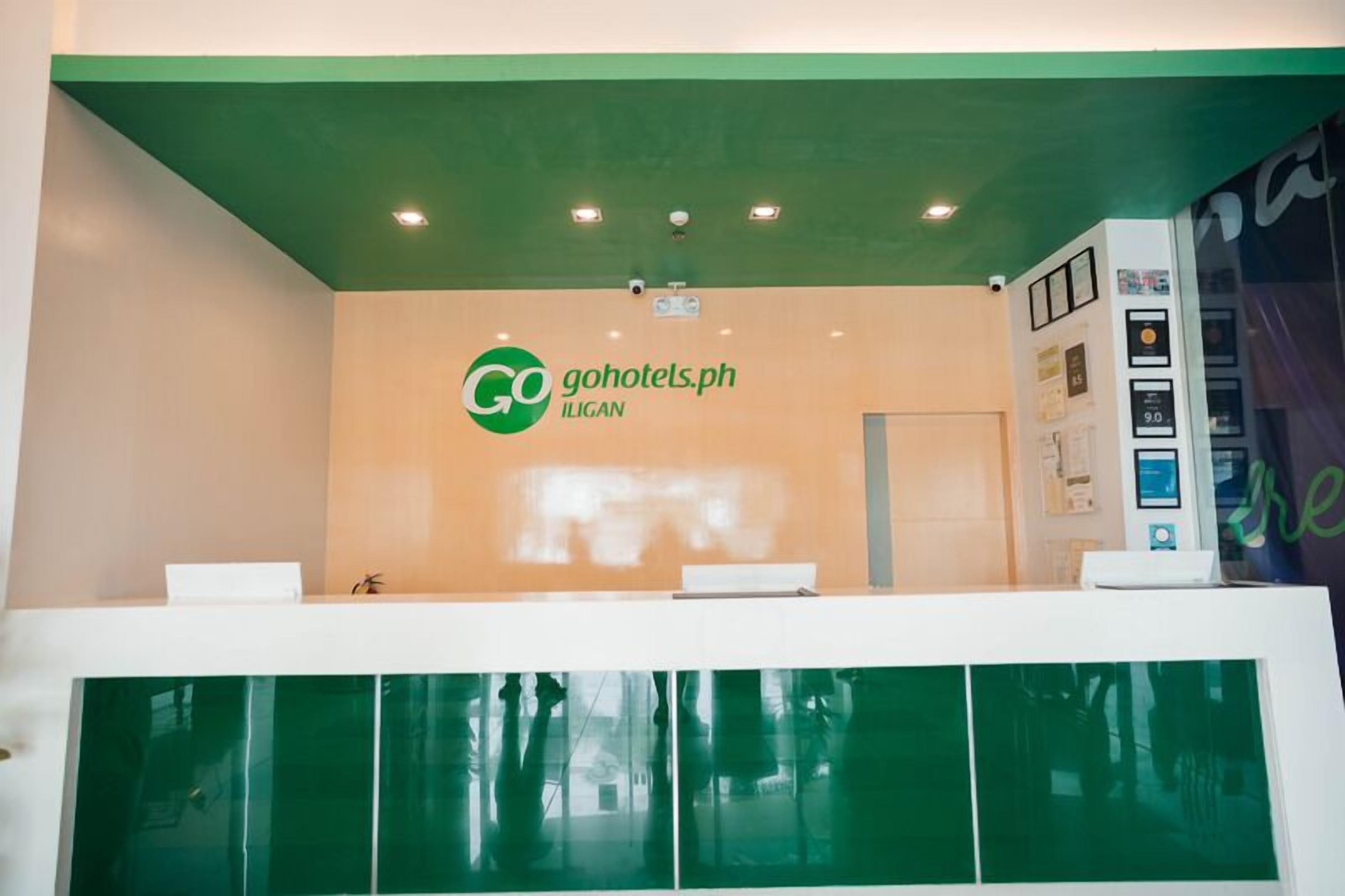 A reception area with a green ceiling, a reception desk, and a wall-mounted information kiosk.