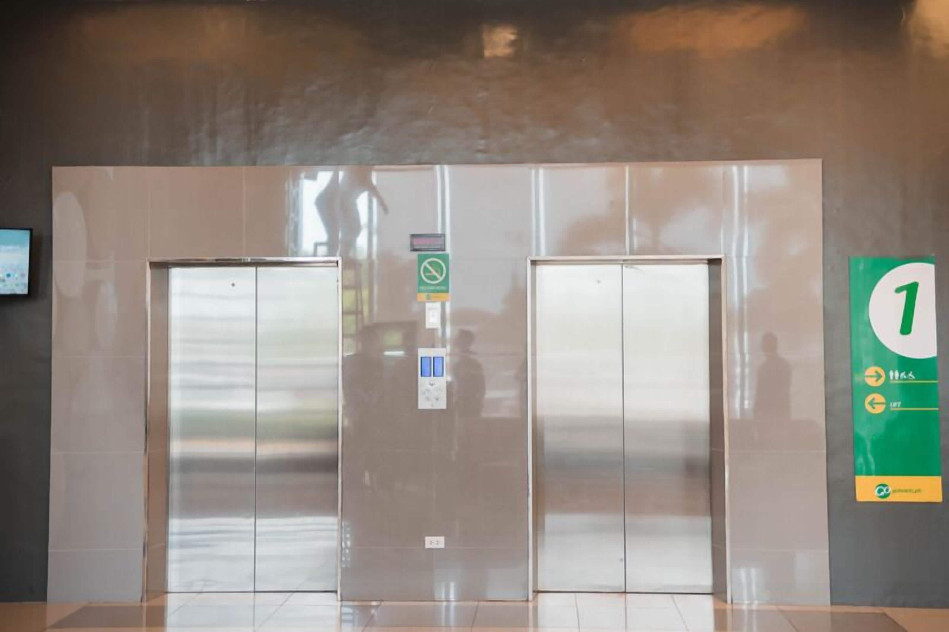 A modern elevator with a digital display, a green directional sign, and a number 1 sign indicating the floor.