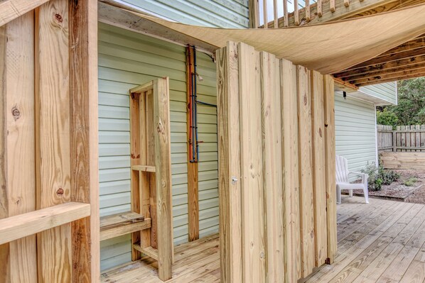 A wooden deck with a covered area, a white chair, and a wooden structure with shelves. - Top-Rated Beach Rental. Super clean & well-appointed. Private heated pool! (Surf City)