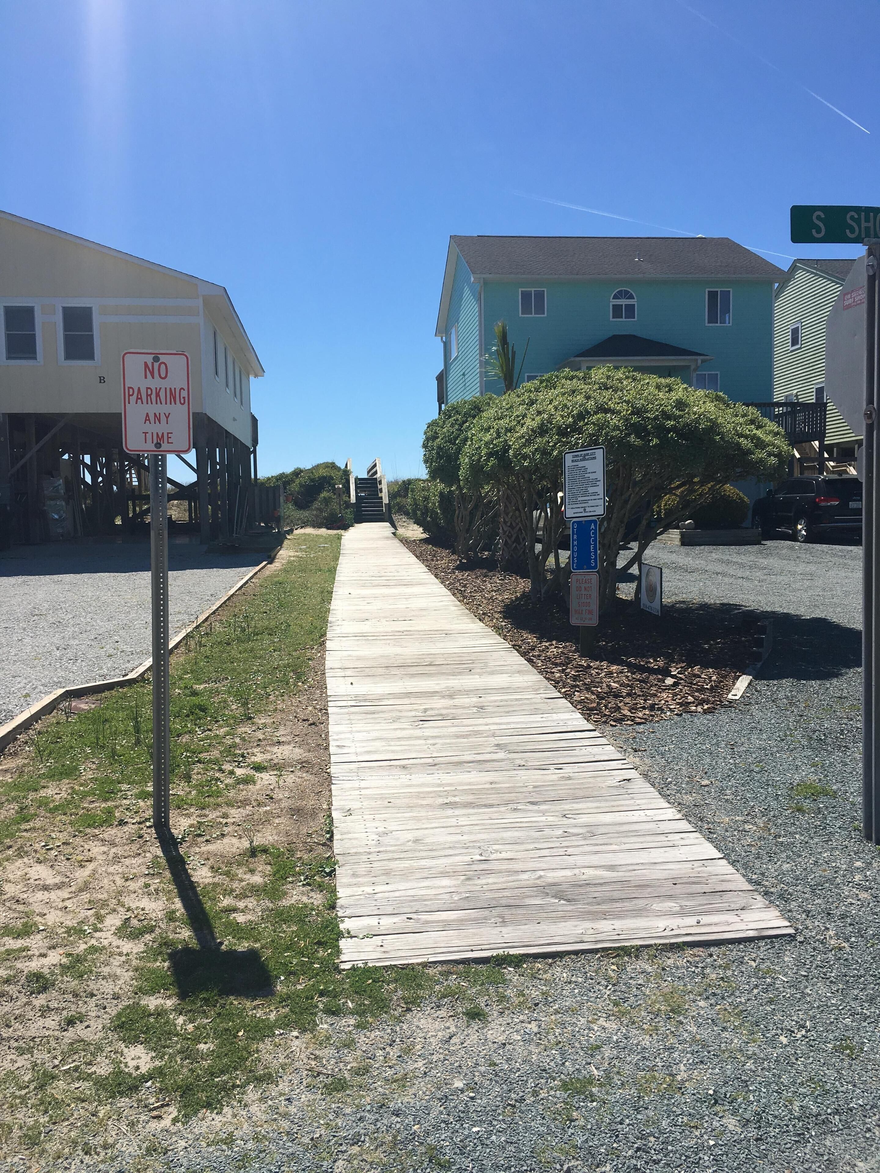 A wooden boardwalk leading to a building with a 'No Parking Any Time' sign.