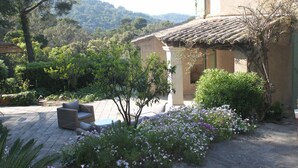 A house with a tiled roof, a garden with flowers, and a patio with furniture.