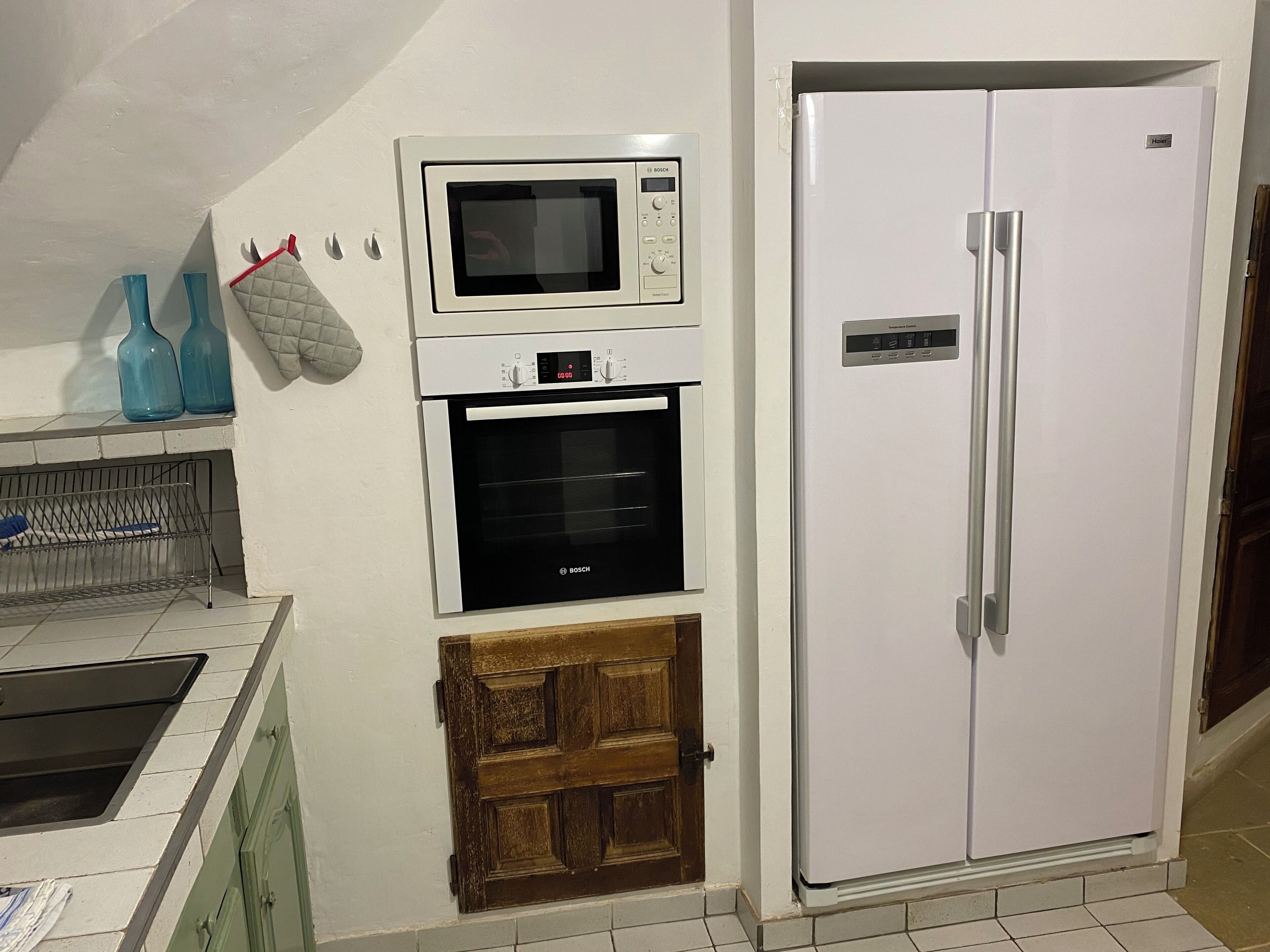 A kitchen with a Bosch microwave, oven, and a white refrigerator.