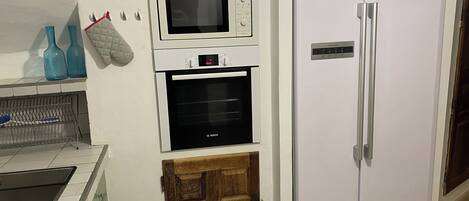A kitchen with a Bosch microwave, oven, and a white refrigerator.