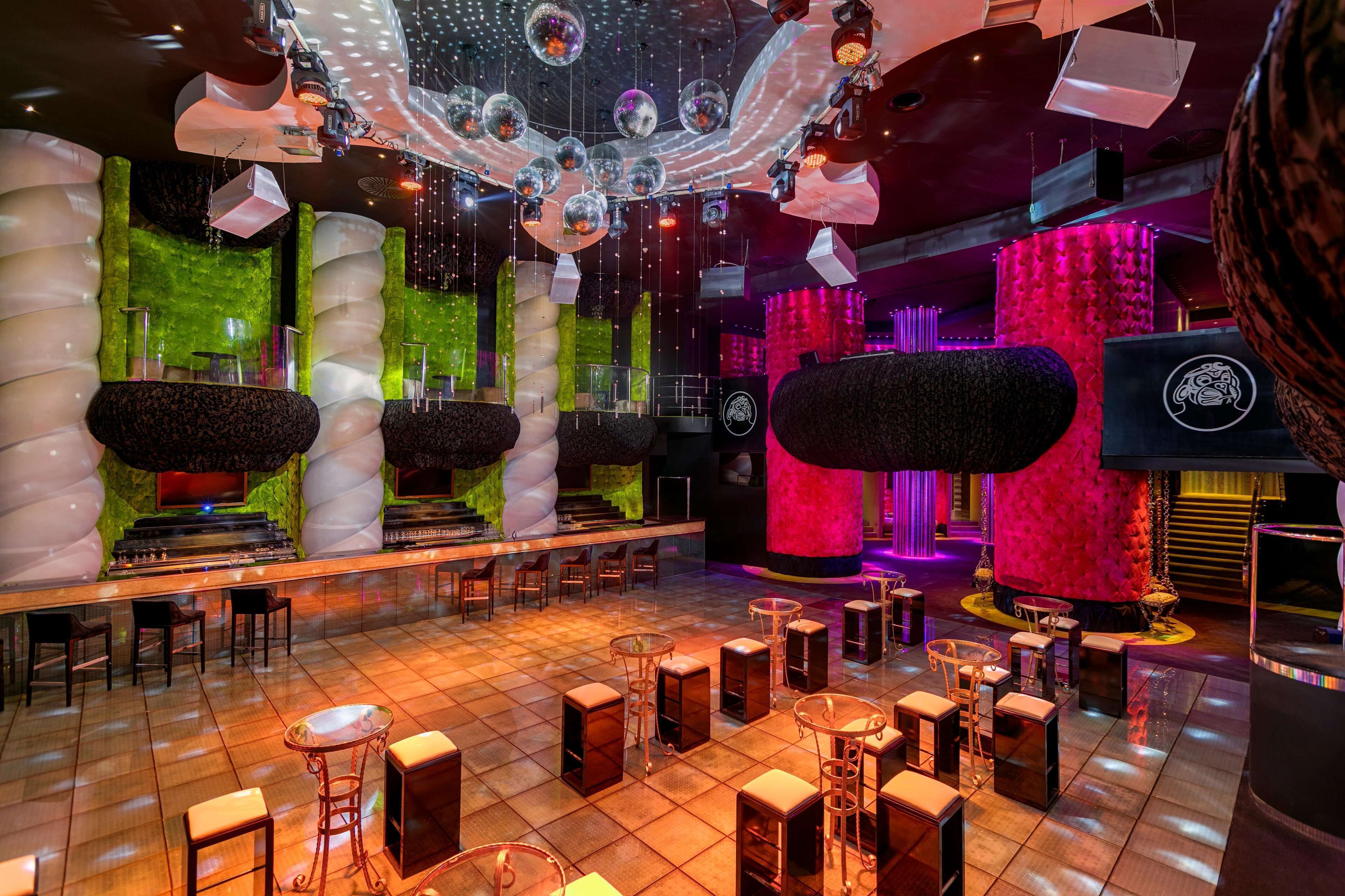 A bar area with a bar counter, stools, and a stage with a red backdrop.