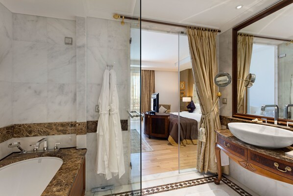 A modern bathroom with a large bathtub, a vanity with a large mirror, and a shower area. - Mardan Palace - All inclusive (Antalya)