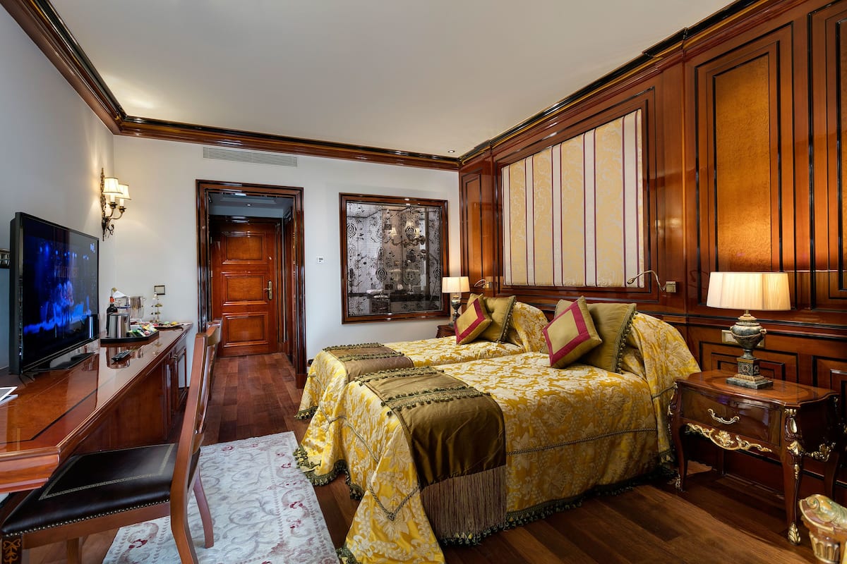 A hotel room with a large bed, a television, a desk with a computer, and a chair.