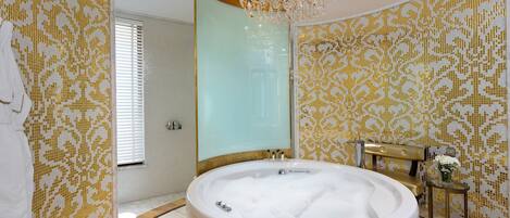 Un baño lujoso con una bañera grande, una araña y paredes con diseños.