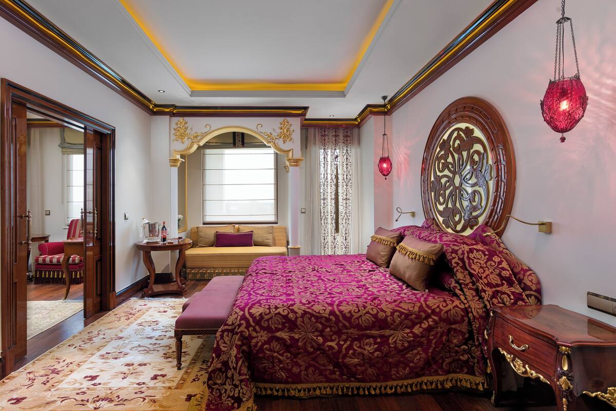 A bedroom with a large bed, a bedside table, a hanging red lantern, and a mirror above the bed.