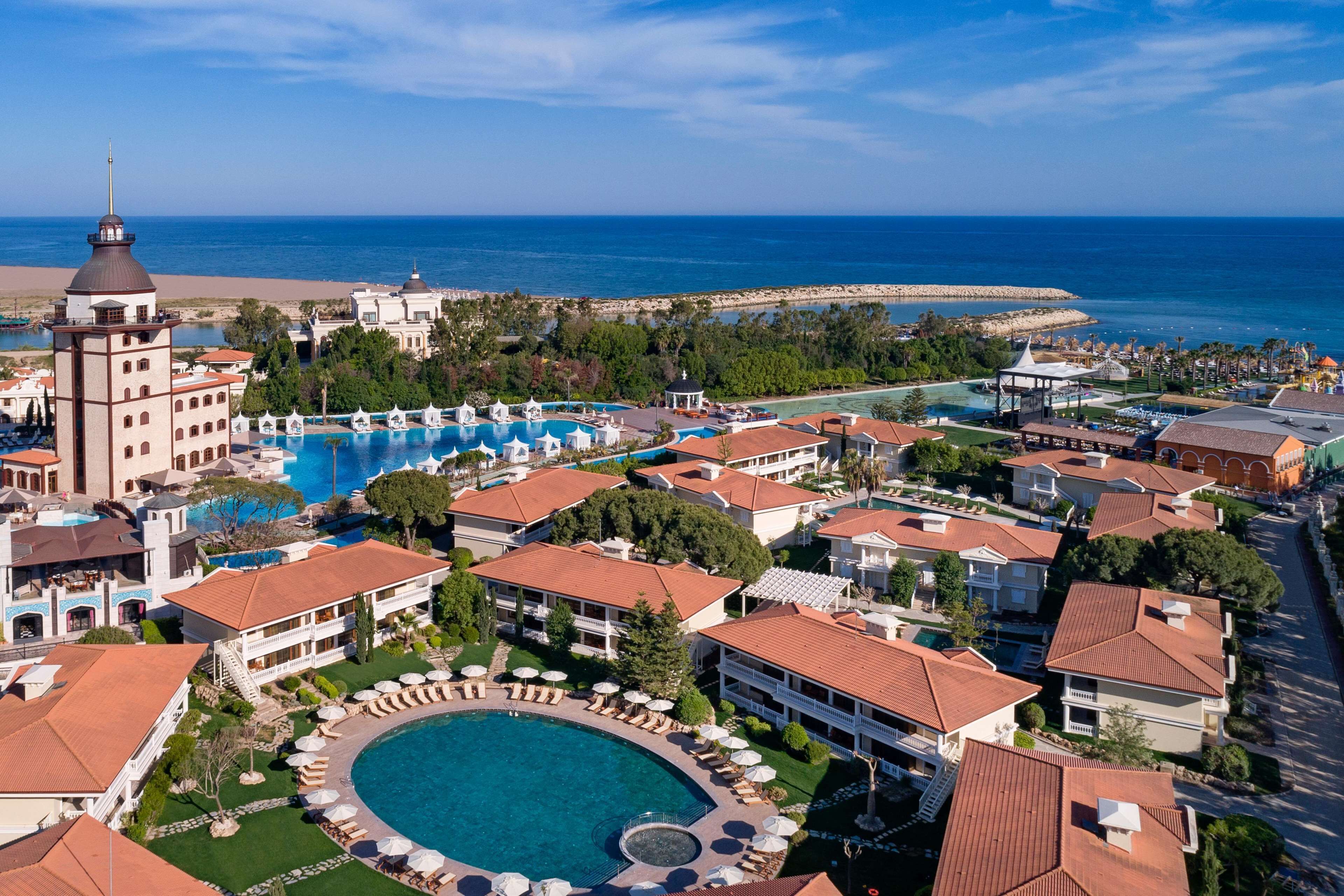 Un resort con una piscina grande, varias construcciones y vista al océano.