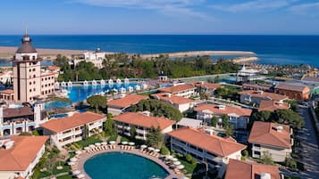 Un resort con una piscina grande, varias construcciones y vista al océano.