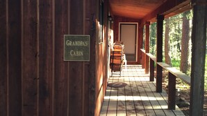 Une cabane en bois portant l’inscription « Cabane du grand-père », avec une véranda et un banc.