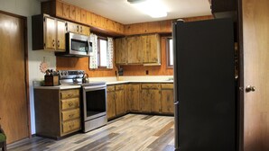 Une cuisine avec des meubles de rangement en bois, un four en acier inoxydable, un four à micro-ondes et un réfrigérateur noir.