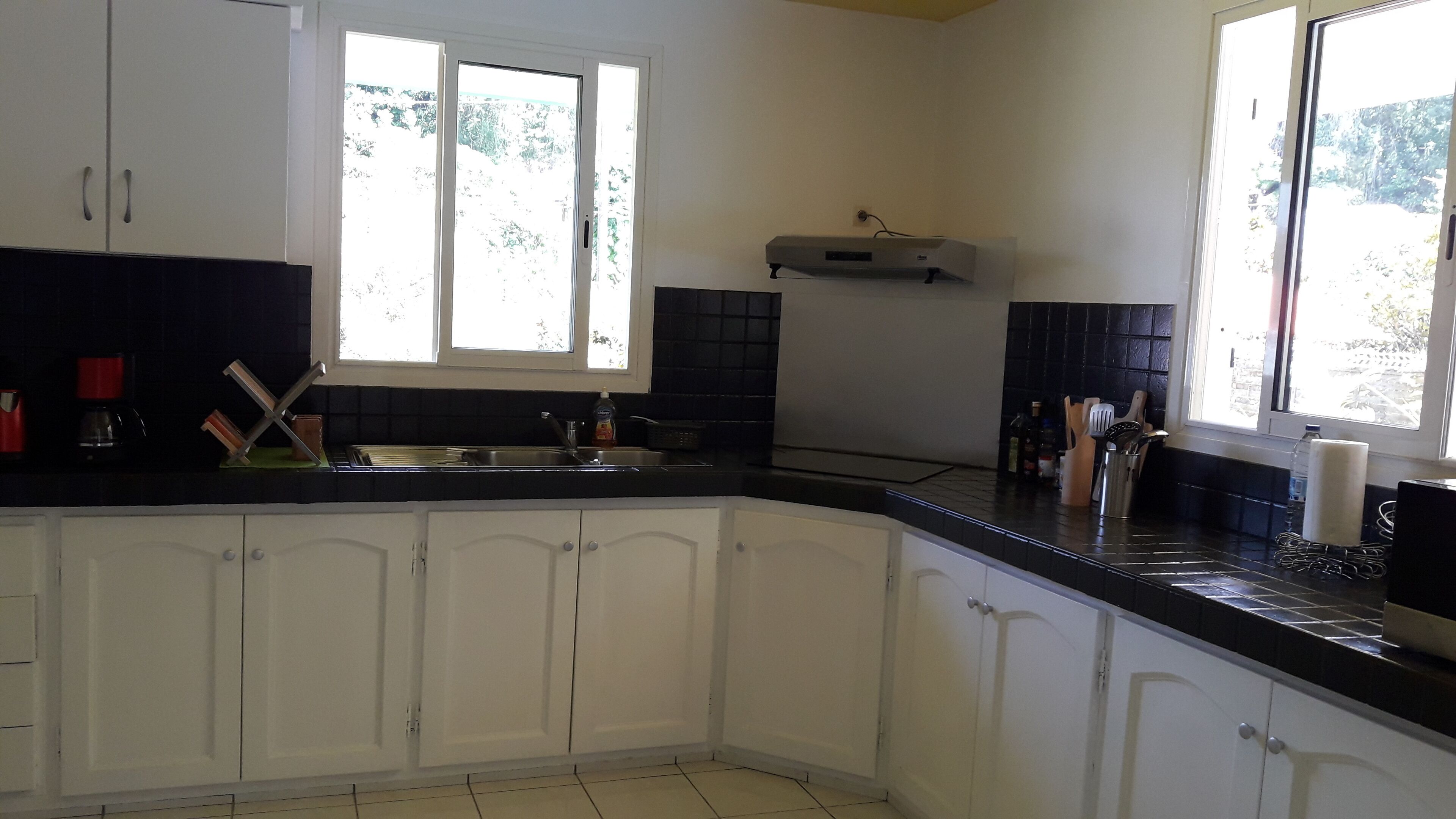 A kitchen with white cabinets, a black countertop, a window, and a built-in microwave.