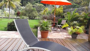 A deck with a lounge chair, a table, and potted plants. - spacious ground floor of 200m² in villa with private pool (Morne à l'Eau)