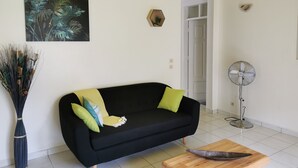 A living room with a black sofa, a wooden coffee table, a floor lamp, a fan, and a painting on the wall. - spacious ground floor of 200m² in villa with private pool (Morne à l'Eau)