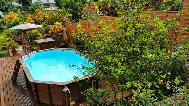 A wooden deck with a hot tub surrounded by lush greenery and a wooden fence. - spacious ground floor of 200m² in villa with private pool (Morne à l'Eau)