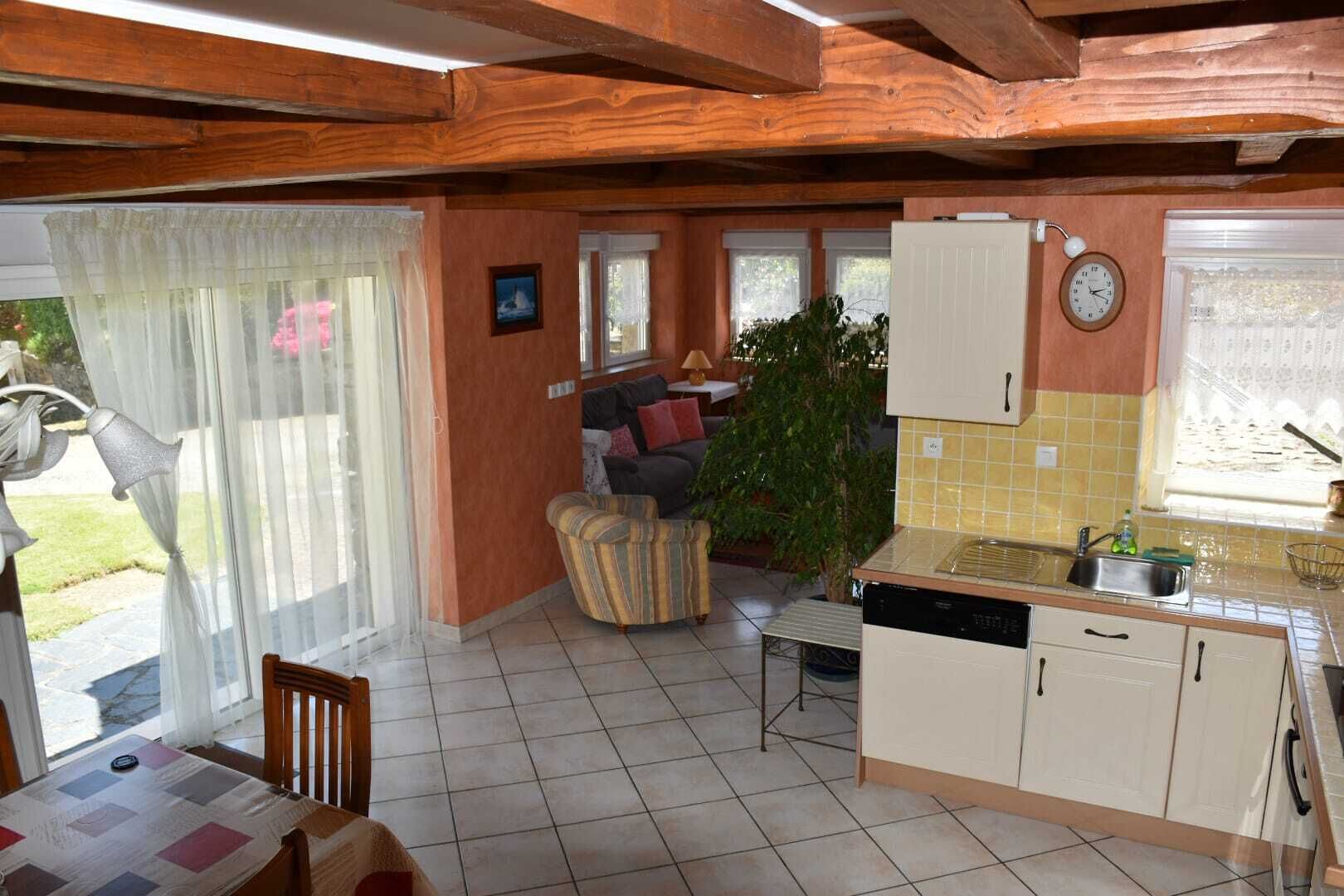 Un espace de vie chaleureux comprenant un canapé, une table à manger et un coin cuisine avec un évier et des placards.