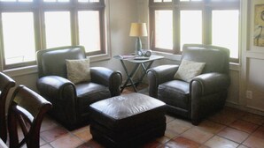 Una habitación con dos sillones de cuero, una mesita con lámpara y un reposapiés a juego.