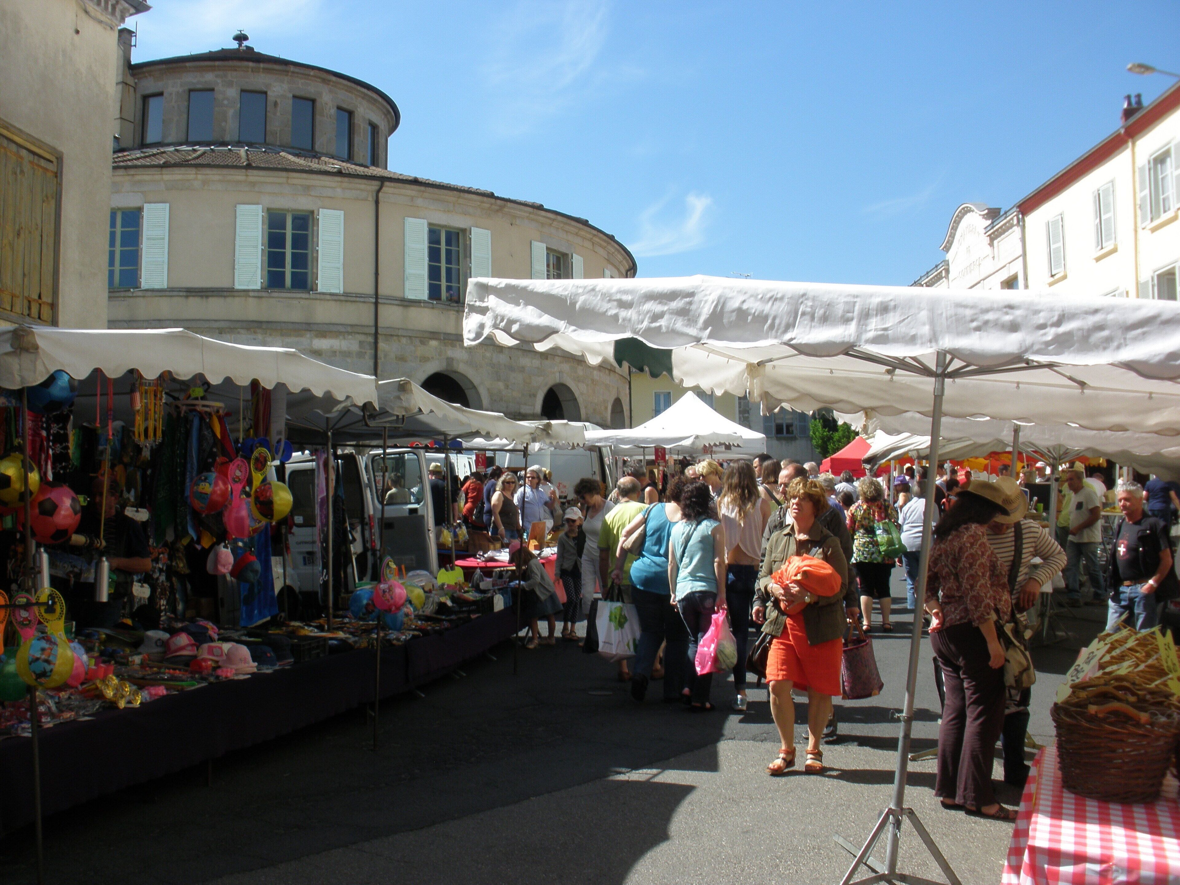 A bustling outdoor market with various stalls and people shopping.