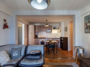 A modern living room with a sofa, a dining table with chairs, and a kitchen in the background. - Charming 4-person apartment, 2 bedrooms facing La Mongie slopes (La Mongie)