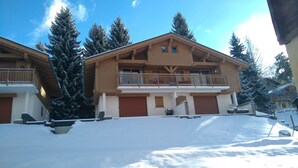 A two-story wooden house with a balcony, surrounded by snow-covered trees. - Apartment for 6 people, nicely decorated, located on the edge of the slopes (Crest-Voland)