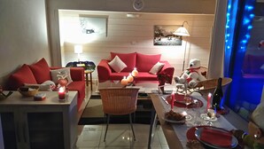 A cozy living room with red sofas, a dining table set for two, and a teddy bear on a chair. - Apartment for 6 people, nicely decorated, located on the edge of the slopes (Crest-Voland)