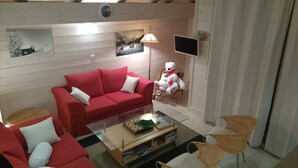 A living room with a red sofa, a glass coffee table, a teddy bear, and a wicker chair. - Apartment for 6 people, nicely decorated, located on the edge of the slopes (Crest-Voland)