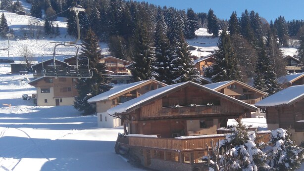 A wooden chalet-style building with a snow-covered roof, surrounded by trees and a ski lift in the background. - Apartment for 6 people, nicely decorated, located on the edge of the slopes (Crest-Voland)
