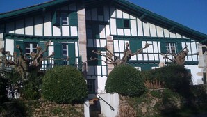 A traditional half-timbered house with a stone wall and a staircase leading to the entrance. - Apartment in Basque house (Sare)