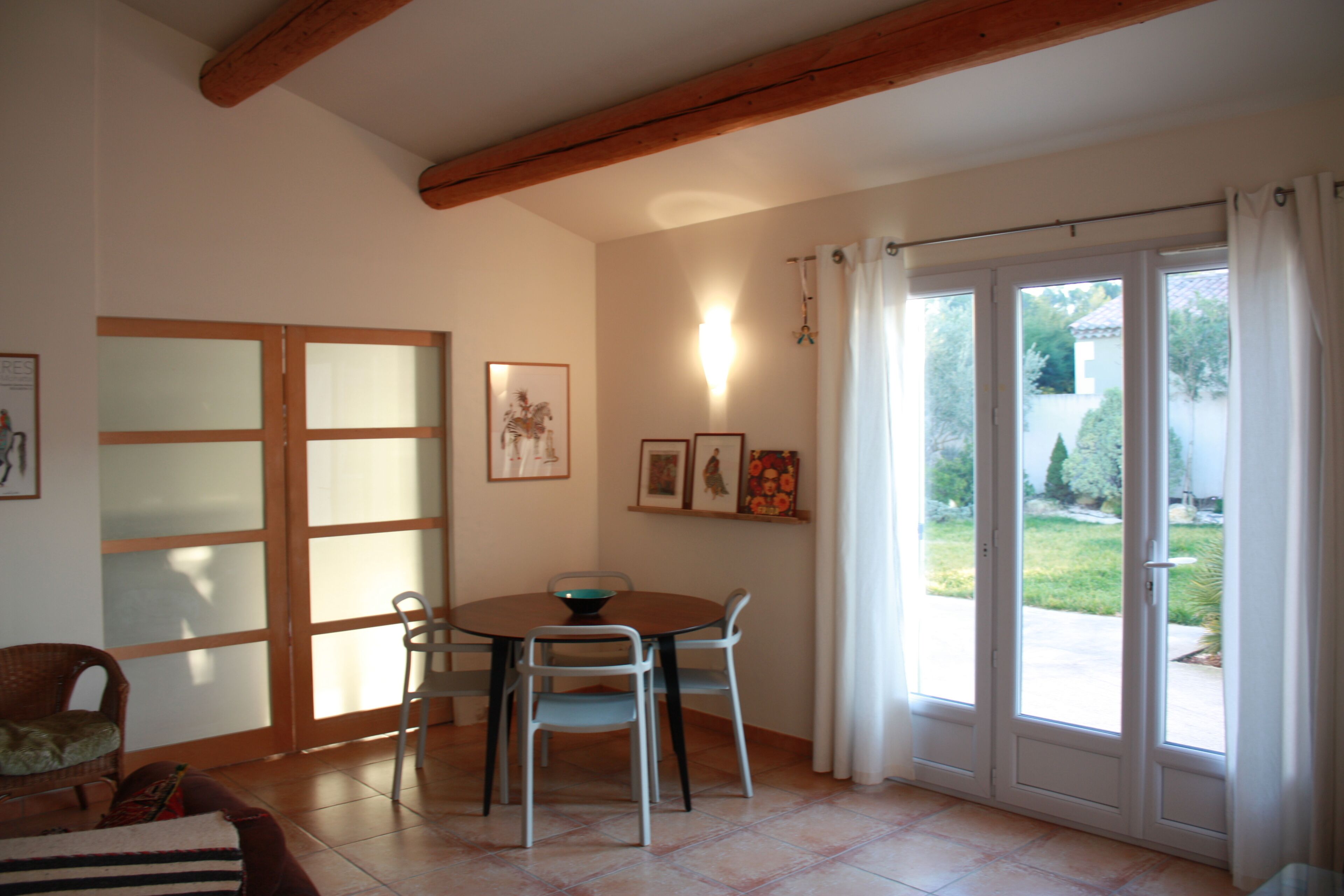 A dining area with a table and chairs, a sofa, and a sliding glass door leading to a garden.