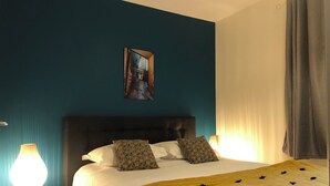Un lit bien fait, agrémenté d’un couvre-lit jaune, de deux coussins à motifs et d’une tête de lit sombre.