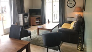 Un salon comprenant un canapé, des fauteuils, une table basse, un téléviseur et une cheminée.
