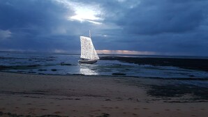 Un voilier sur une plage, sous un ciel nuageux.