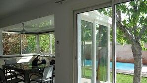 A modern kitchen with a dining area, large windows, and a view of a swimming pool.