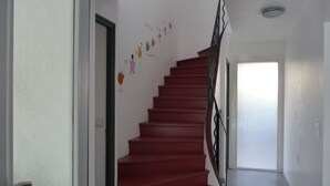 A staircase with red steps and a black railing, leading to a room with a white door.
