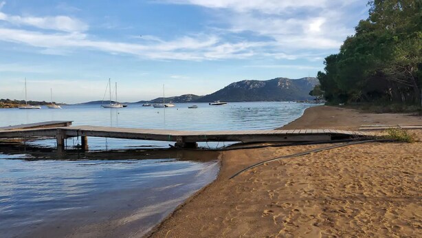 A beach with a wooden pier extending into calm waters, surrounded by mountains and sparse vegetation. - I mini villa 4/6 pers with swimming pool in Porto vecchio (Porto-Vecchio)