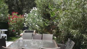 An outdoor patio with wicker furniture, surrounded by greenery and flowering plants. - I mini villa 4/6 pers with swimming pool in Porto vecchio (Porto-Vecchio)