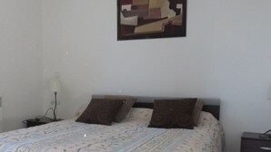A bedroom with a bed, two pillows, a nightstand, a lamp, and a painting on the wall. - Vacation rentals in Arcangues apartment in a villa (Arcangues)