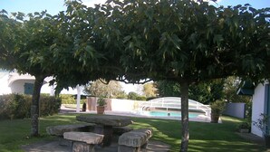 A garden with a stone bench, a pool, and a white building in the background. - Vacation rentals in Arcangues apartment in a villa (Arcangues)
