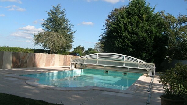 A swimming pool with a white bridge, surrounded by a concrete deck and a stone wall. - Vacation rentals in Arcangues apartment in a villa (Arcangues)