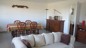 A living room with a sofa, a dining table with chairs, a wooden cabinet, and a wall-mounted shelf. - Vacation rentals in Arcangues apartment in a villa (Arcangues)
