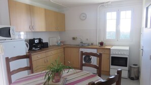 A compact kitchen with wooden cabinets, a microwave, a coffee maker, a sink, and a window. - Vacation rentals in Arcangues apartment in a villa (Arcangues)