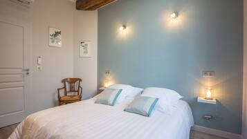 Een slaapkamer met een bed, twee bedlampen, een stoel en een kunstwerk aan de muur.