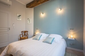 Une chambre à coucher comprenant un lit, deux lampes de chevet, une chaise et des œuvres d’art accrochées au mur.