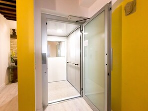 A hallway with a glass door leading to a room.