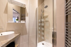 A modern bathroom with a glass-enclosed shower, a white sink, and a mirror above it.